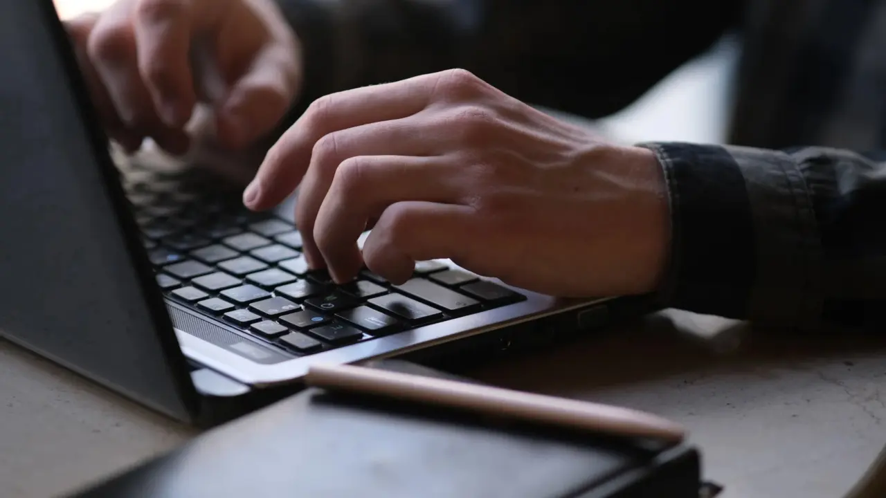 Writer typing a tech article on a laptop